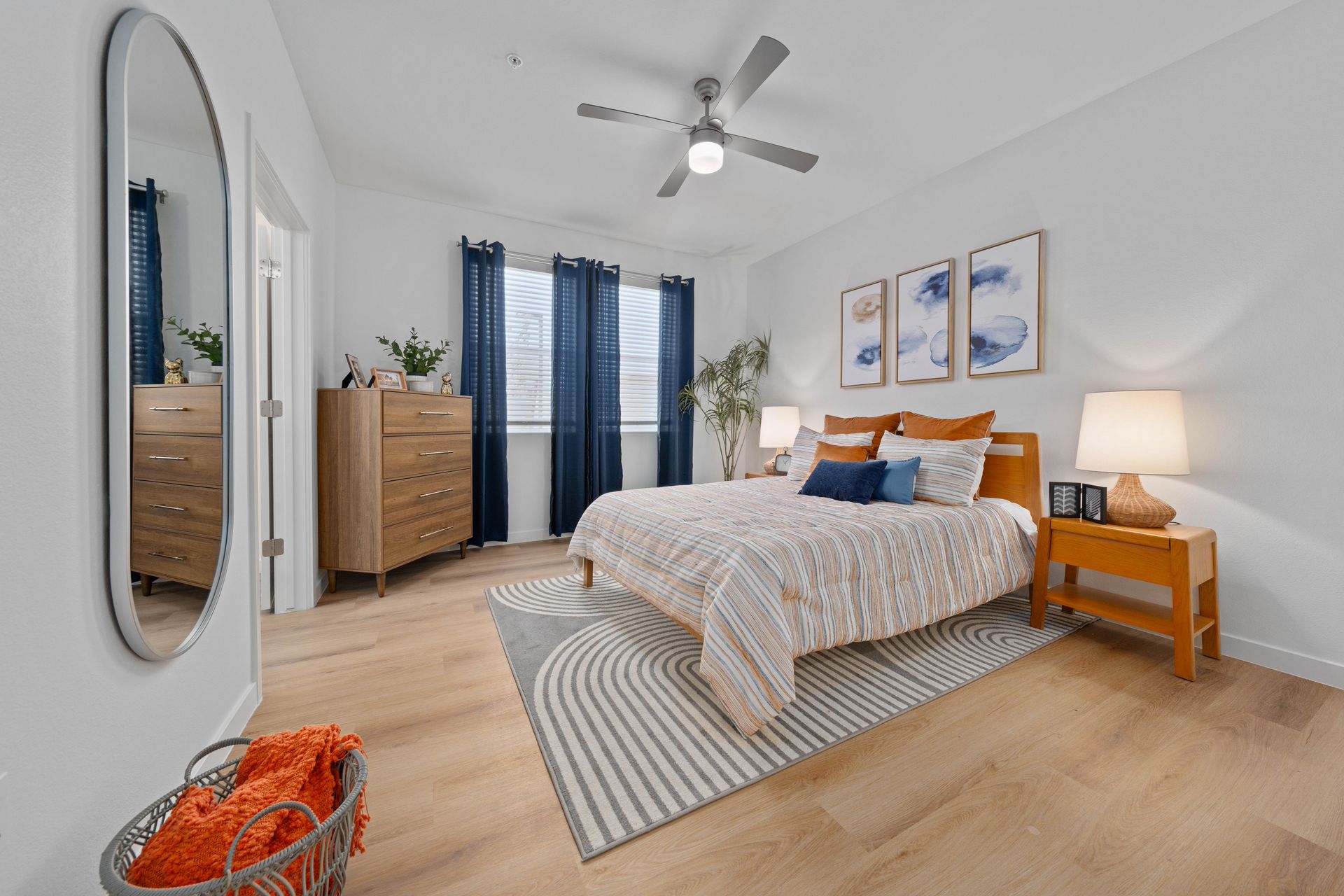 Bedroom with a bed, wooden furniture, blue curtains, and white walls.