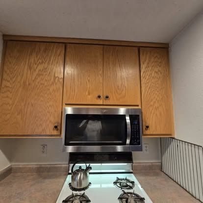 Woman in straw hat smiles, holding wine glass near a lake.