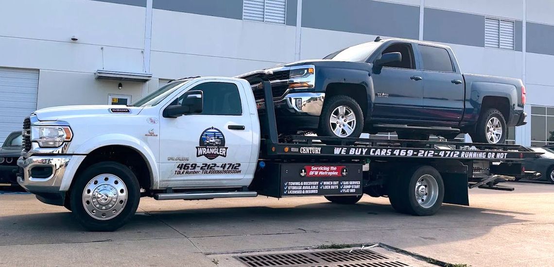 White tow truck carrying a blue pickup truck.
