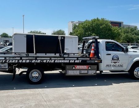 White tow truck with a white box on the flatbed, parked on a sunny day.
