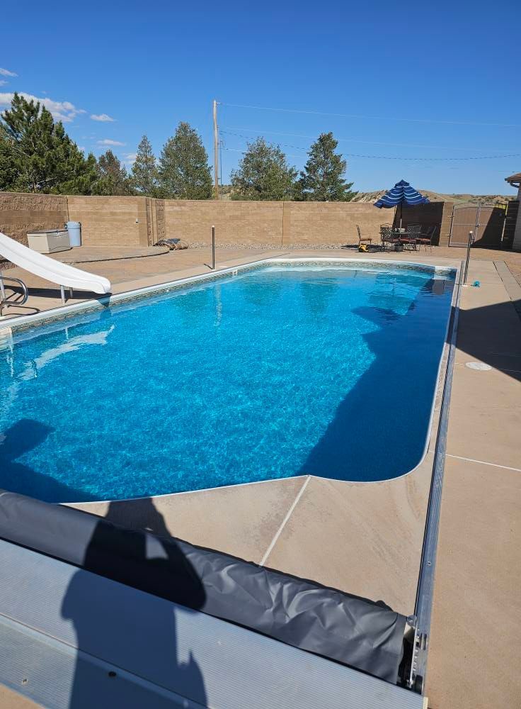 A large swimming pool with a slide and umbrella