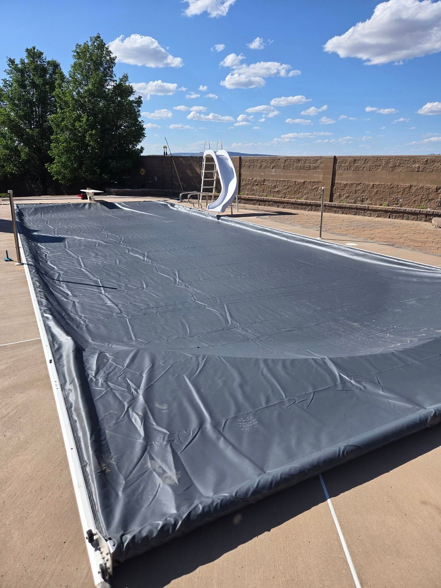 A large black tarp is covering a swimming pool.