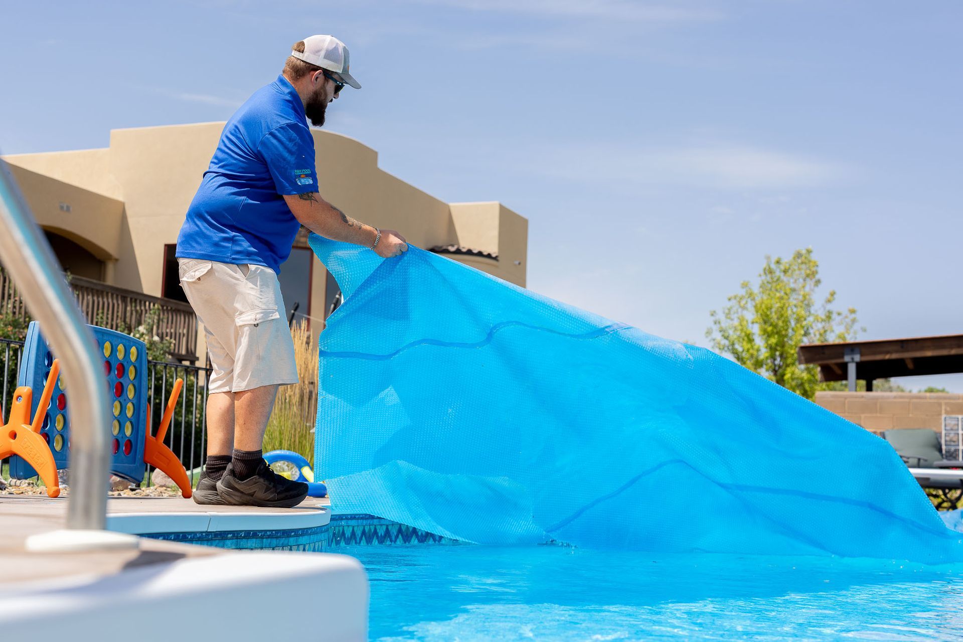 A large swimming pool is surrounded by a brick patio and chairs.