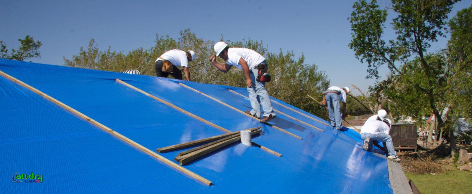 A group of people are working on a blue roof.