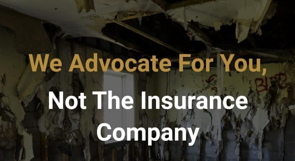 A man wearing a black shirt with a shield on it smiles with his arms crossed