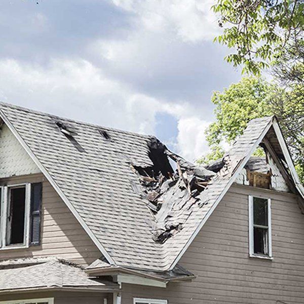 A house with a roof that has been damaged by a storm.