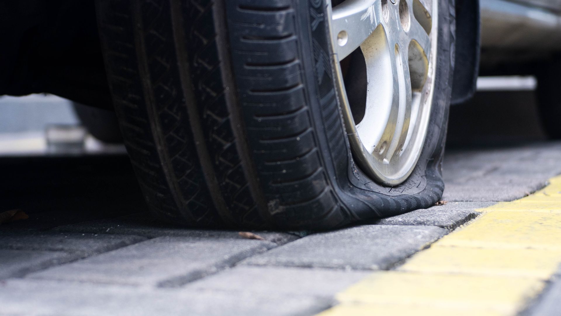 A car with a flat tire on the side of the road.