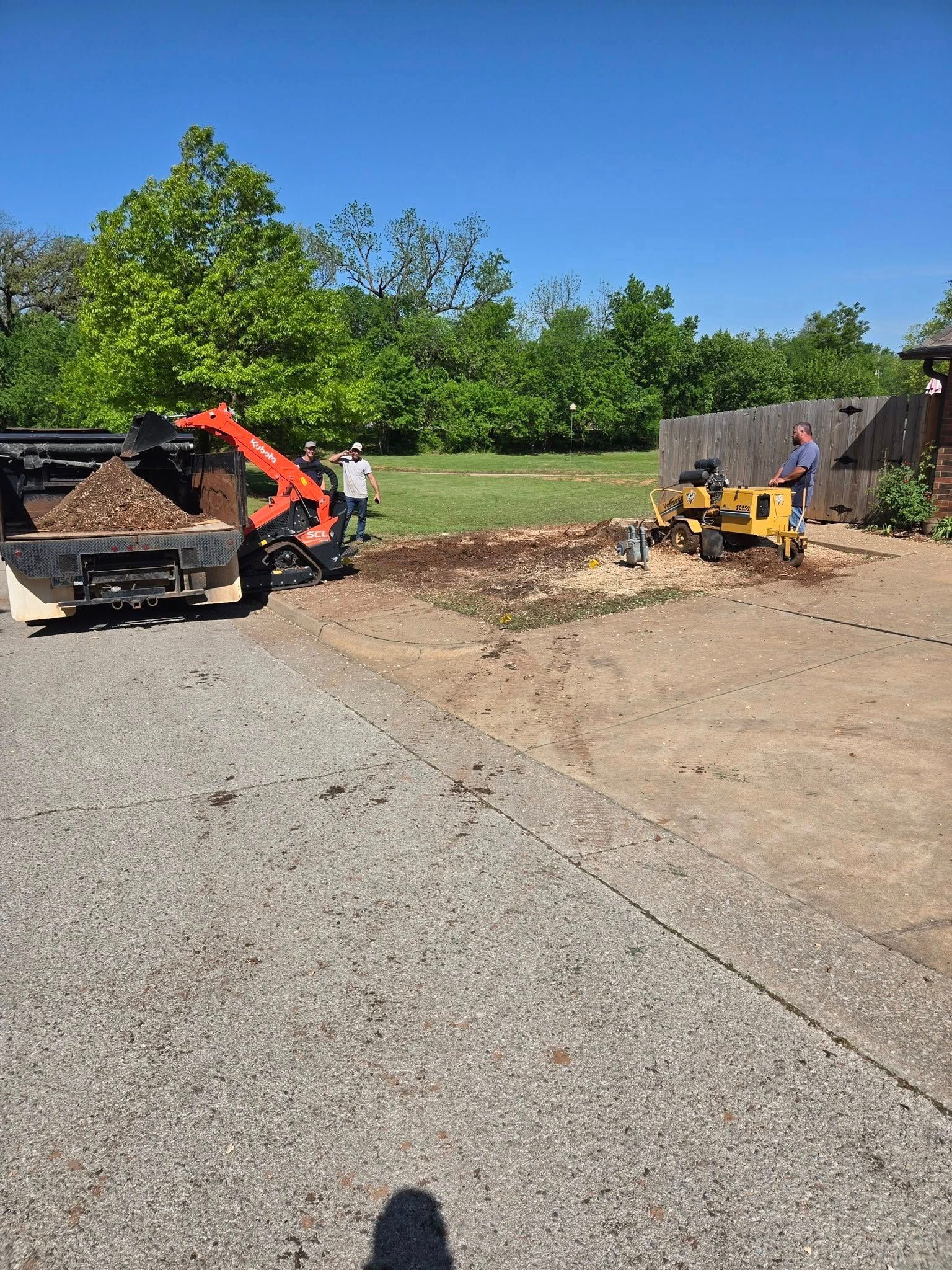 A stump grinder is being used to remove a tree stump from a yard.