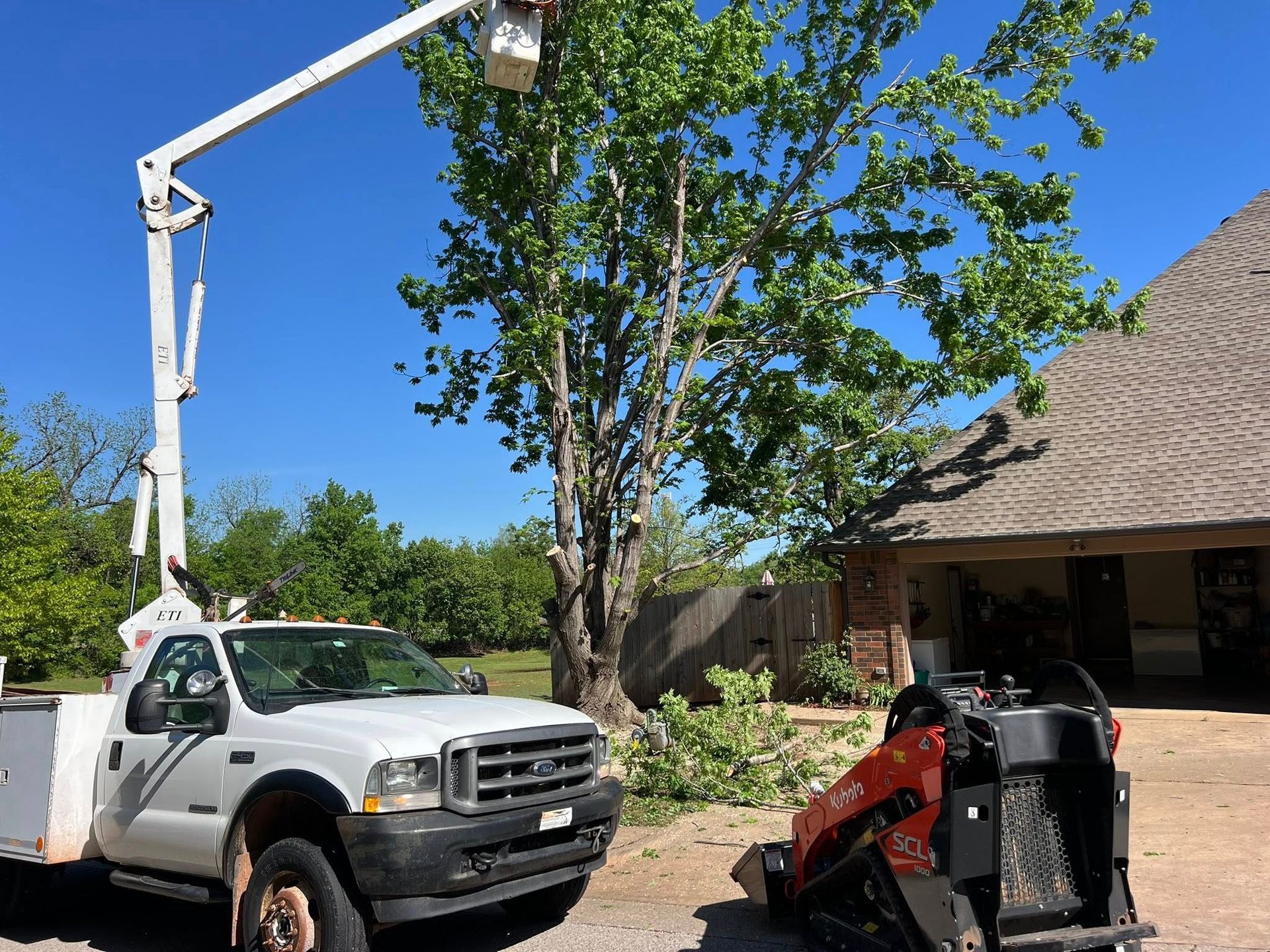 A white truck with a crane on top of it is parked in front of a house.