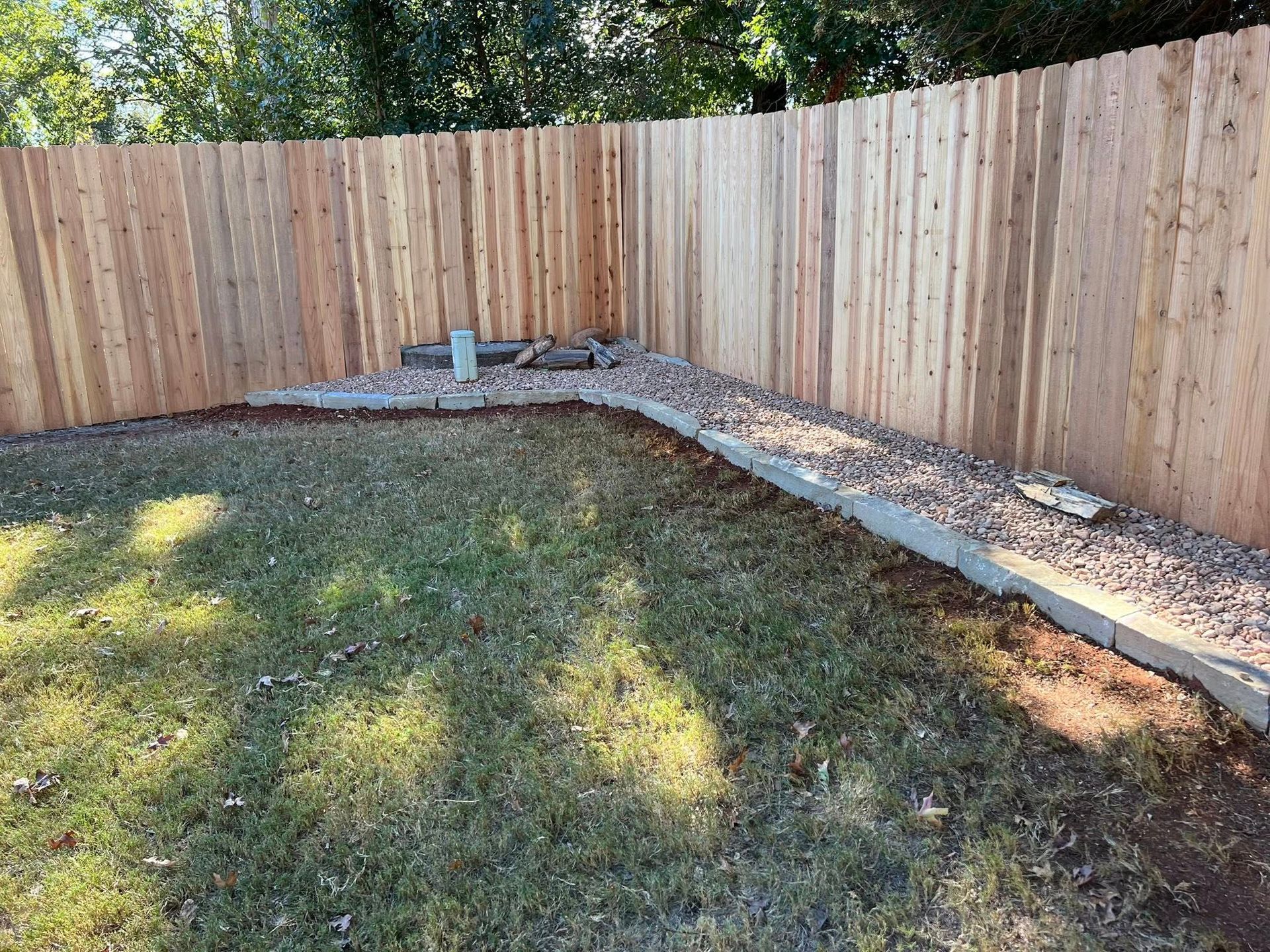 A wooden fence surrounds a lush green lawn in a backyard.