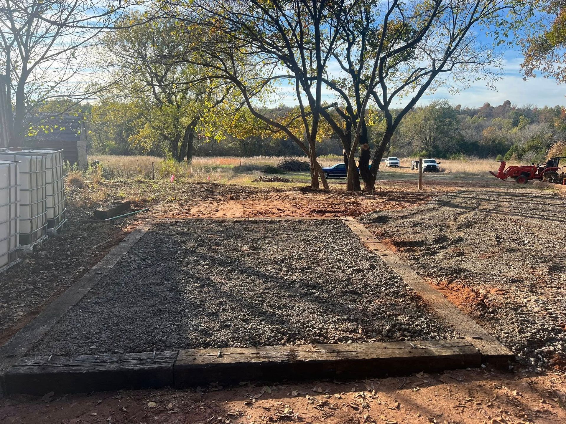 A dirt road with a fence and trees in the background.