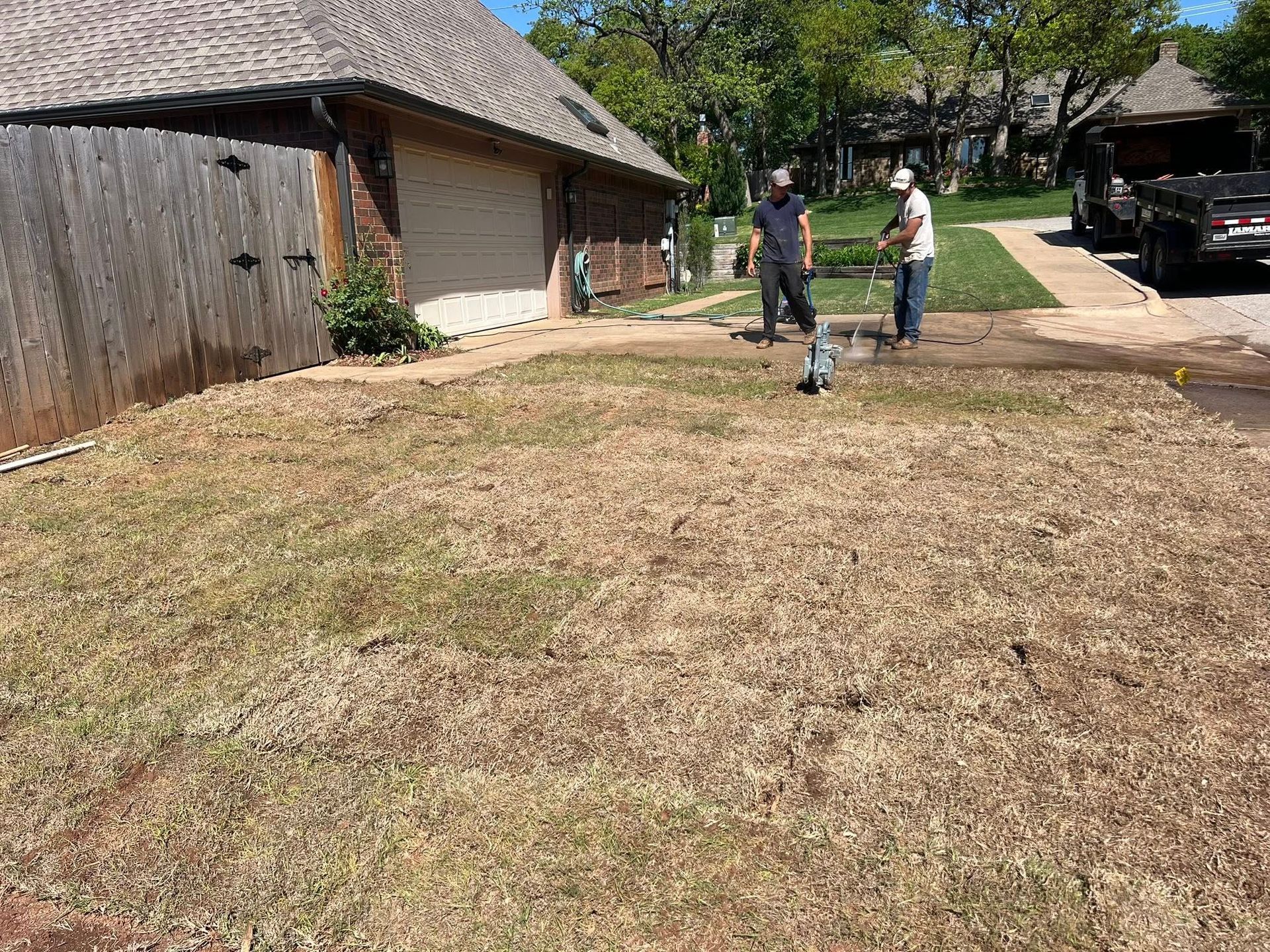 Two men are working on a lawn in front of a house.