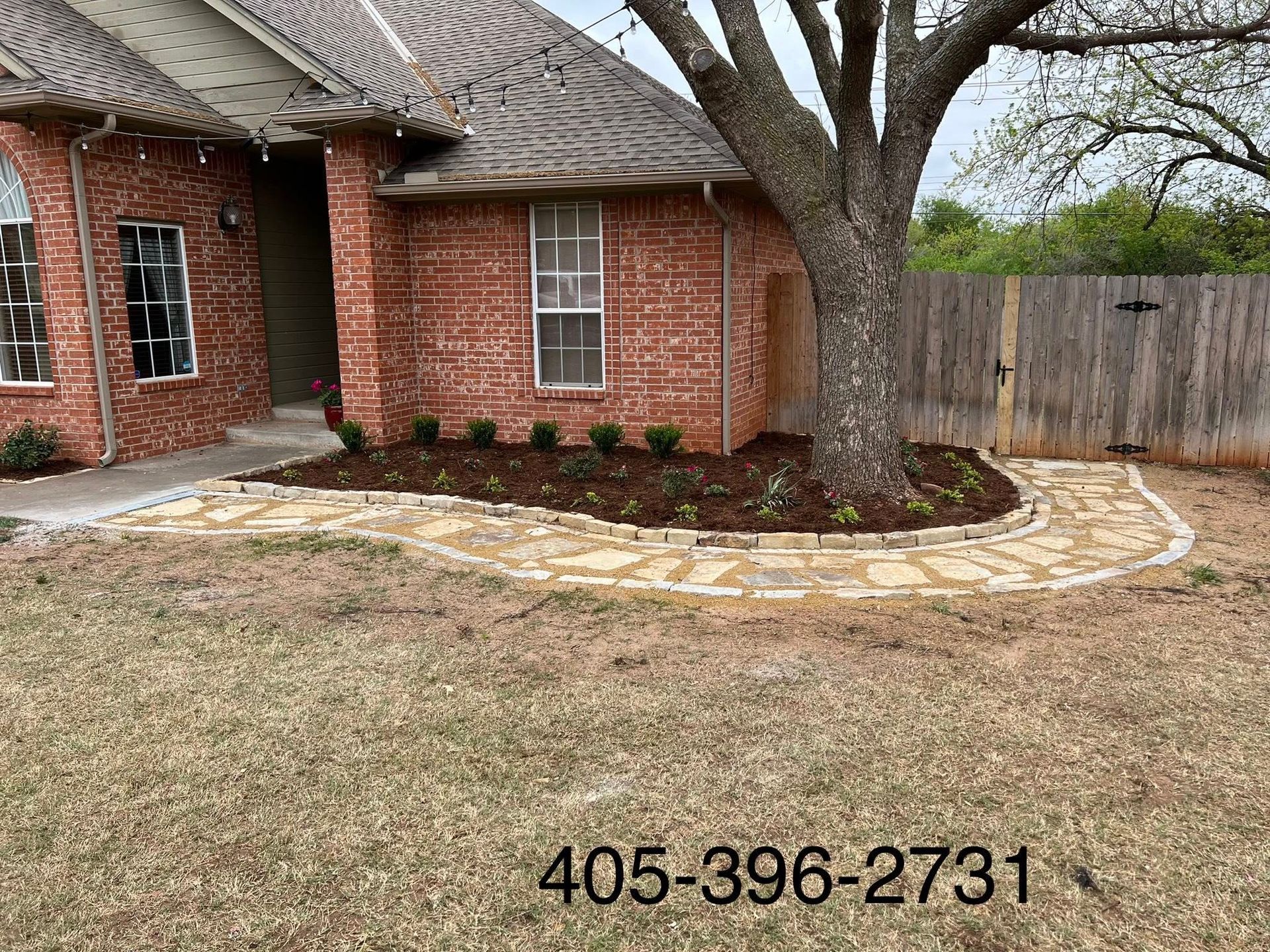 A brick house with a stone walkway and a tree in front of it.