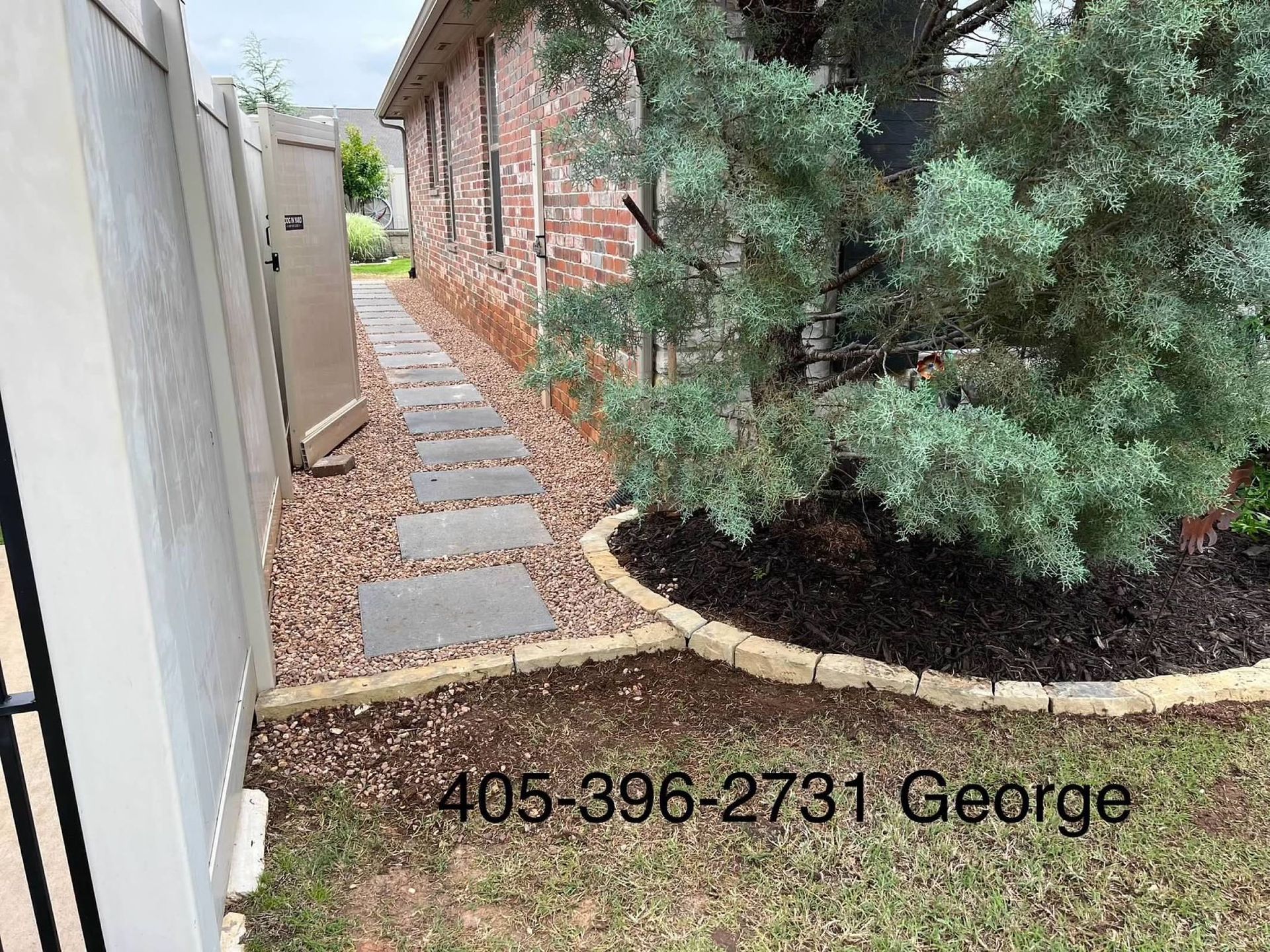 A sidewalk leading to a house with a fence and a tree.