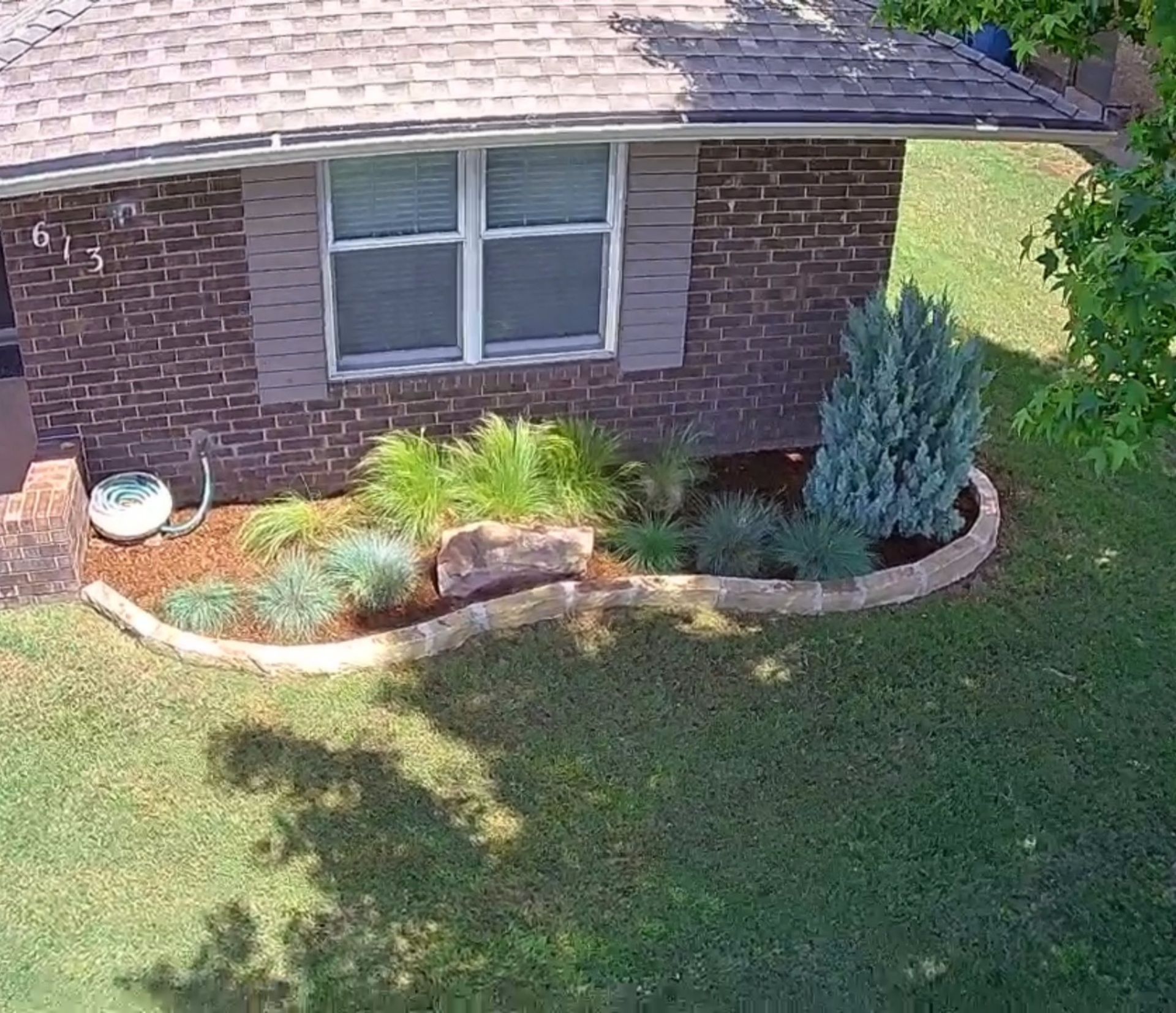 An aerial view of a brick house with a garden in front of it