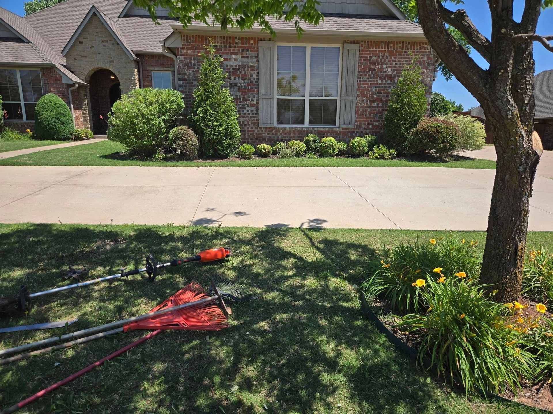 A lawn mower is sitting in the grass in front of a brick house.