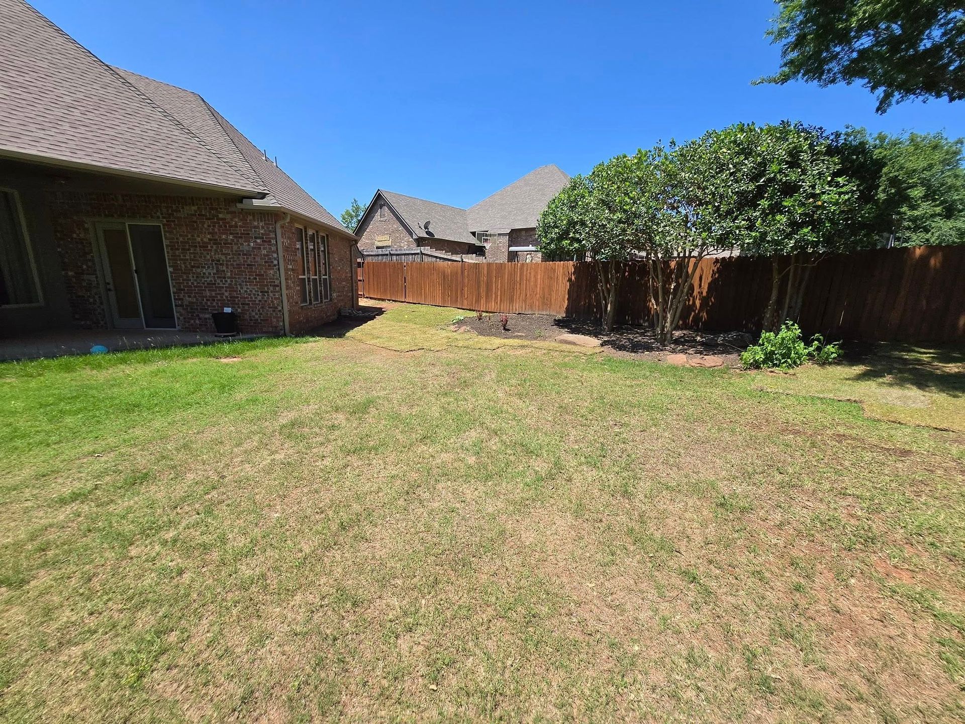 A backyard with a fence and a house in the background.