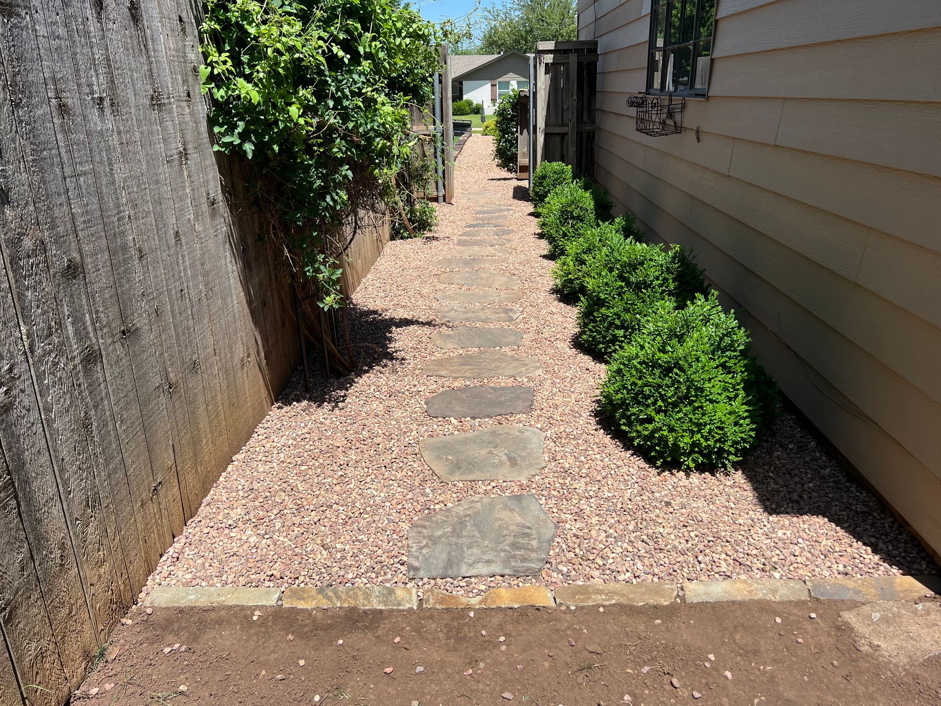A stone walkway leading to the side of a house