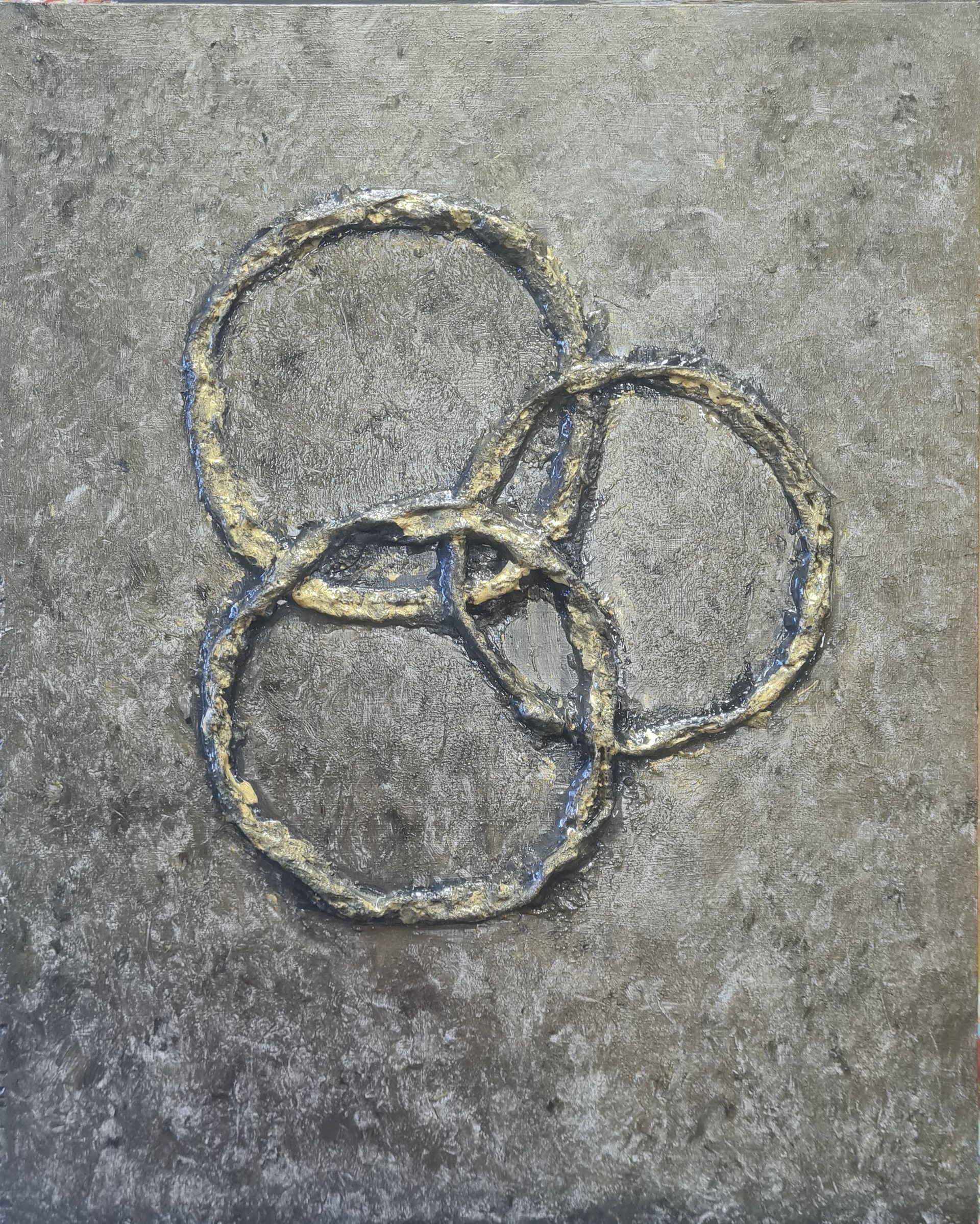 Een close-up gemaakt met gips en acrylverf  van drie ringen op een grijs oppervlak