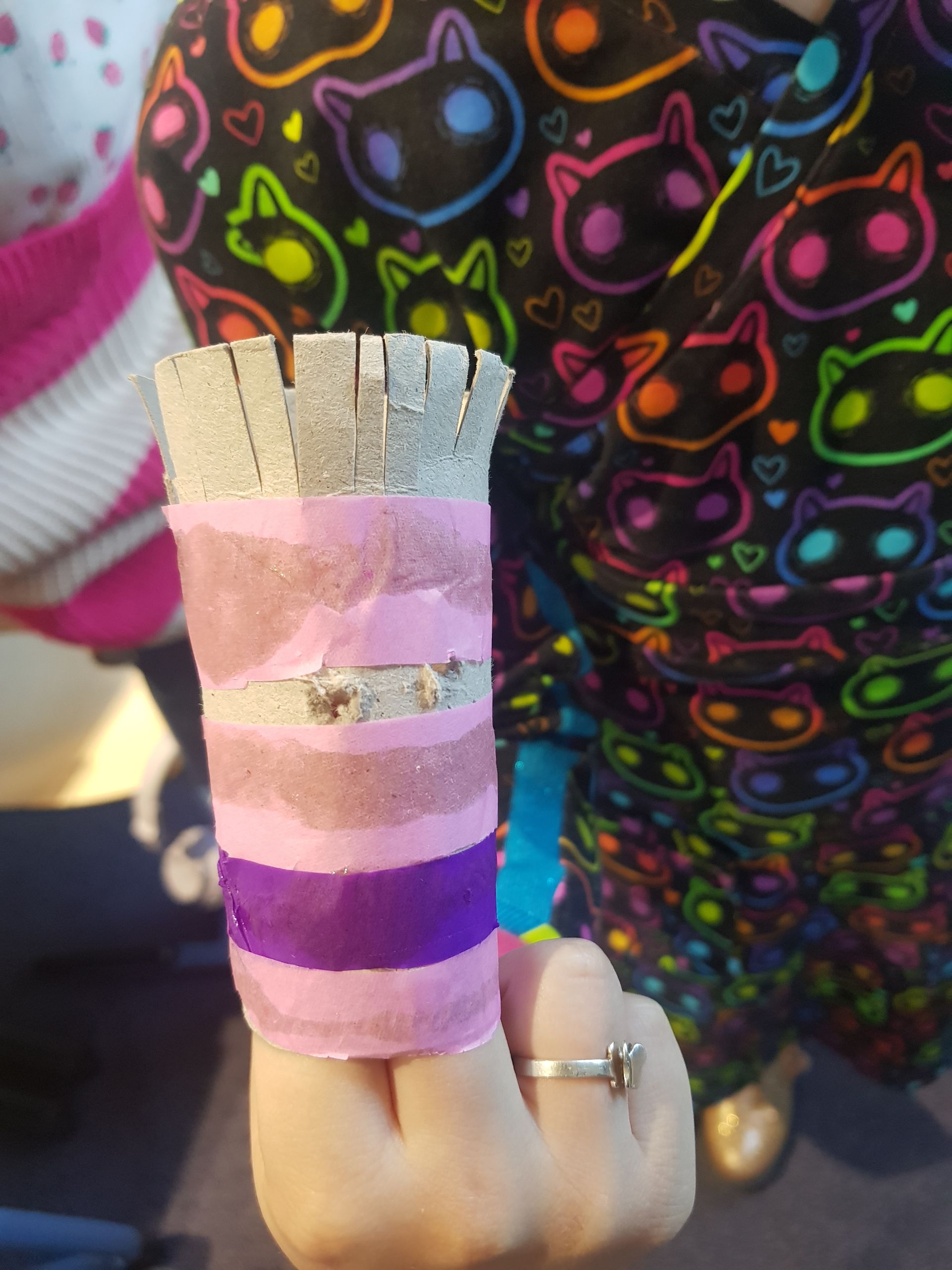 Een persoon die een ring draagt, houdt een roze en paars gestreept voorwerp vast