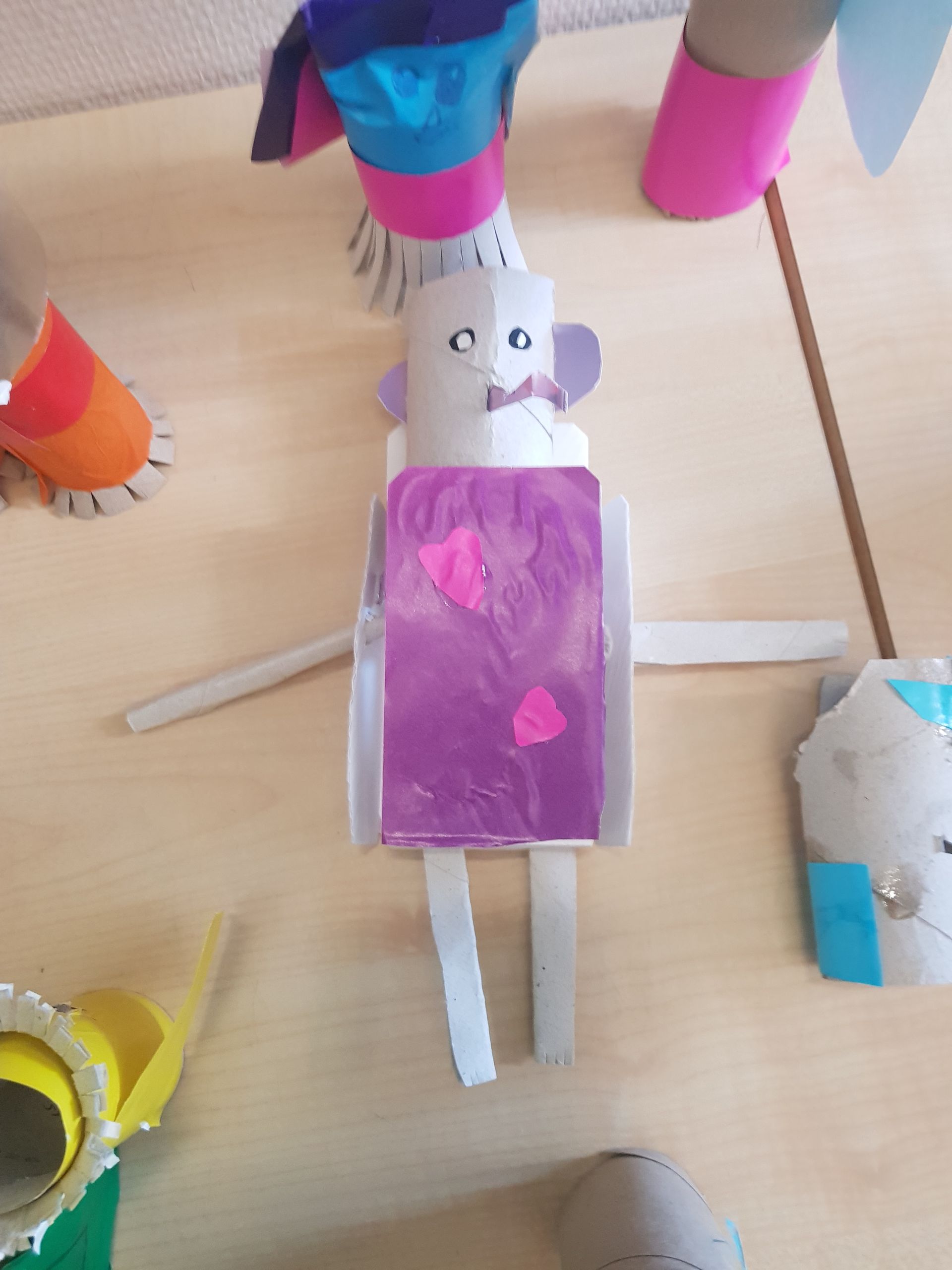 Een muis gemaakt van wc-papierrollen zit op een tafel