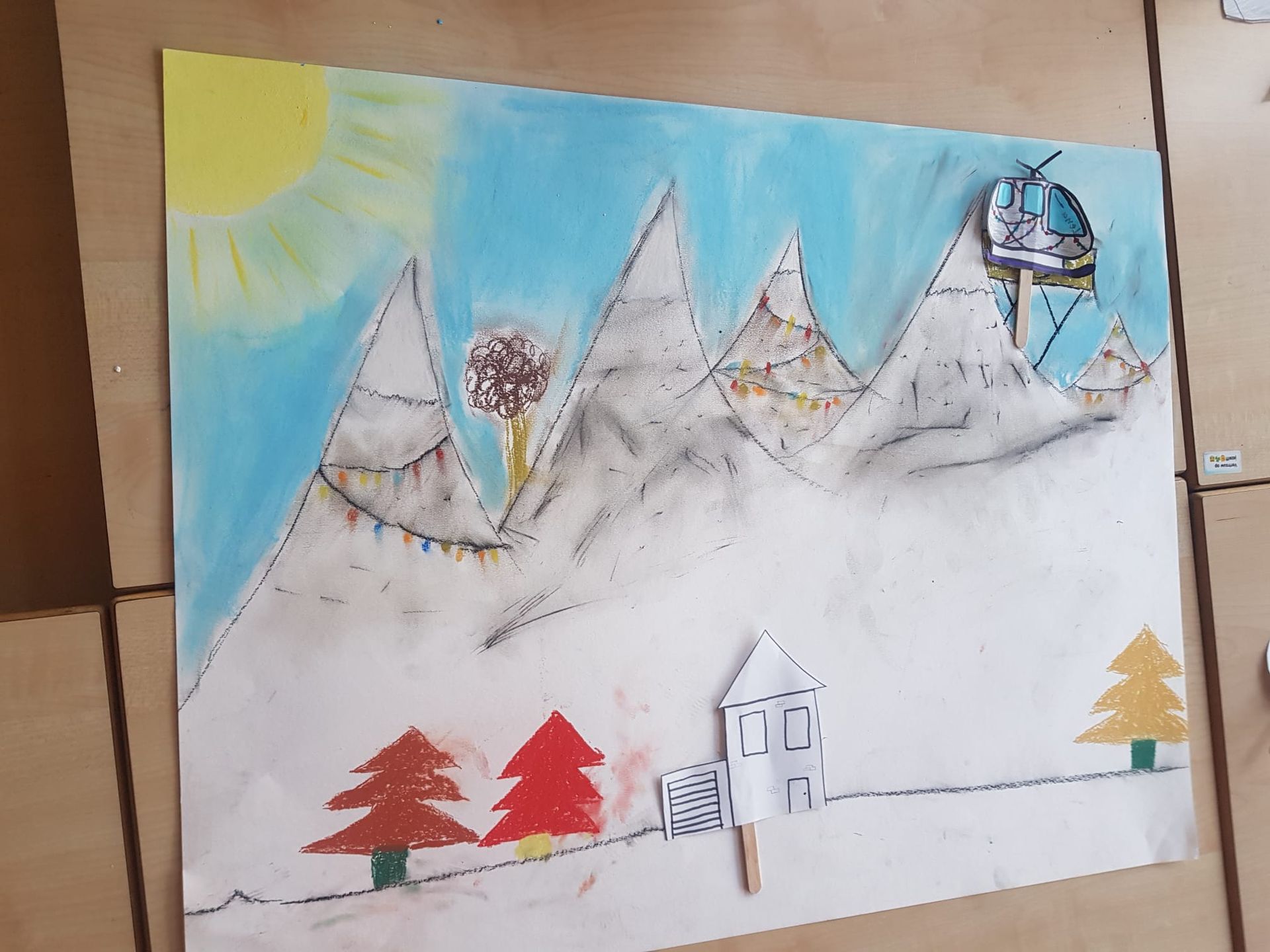 Een kindertekening van een berglandschap in de winter met een skilift in de bergen