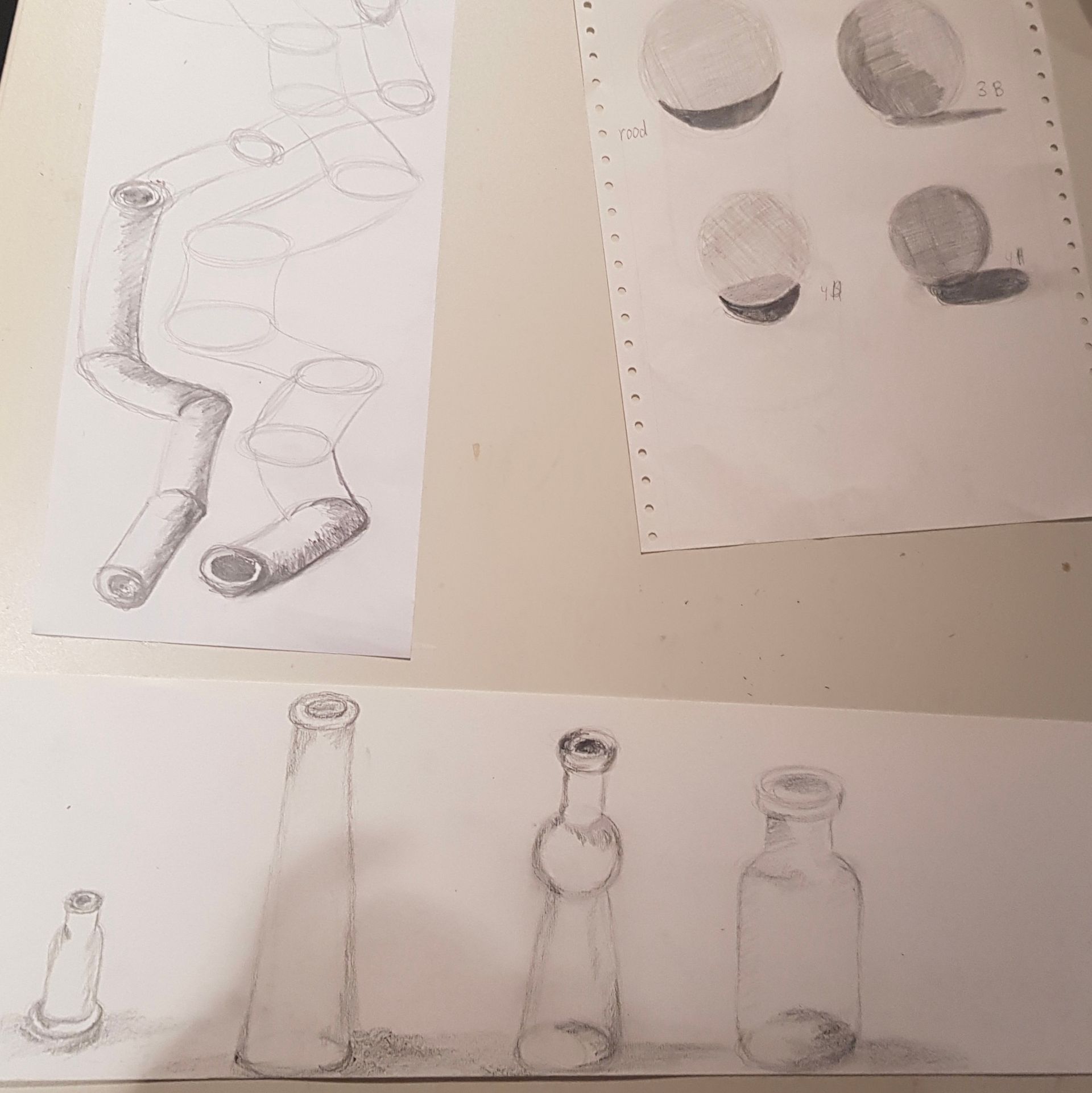 Op een tafel staan verschillende tekeningen van flessen en ballen