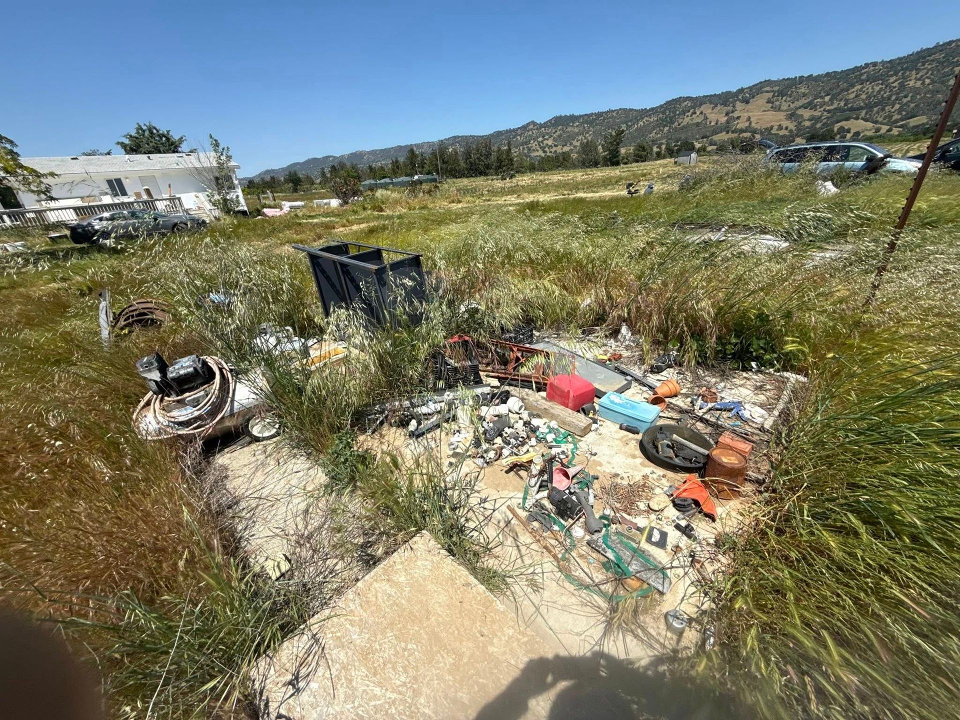 A field with trash and debris. Mountains in the background. Blue sky.