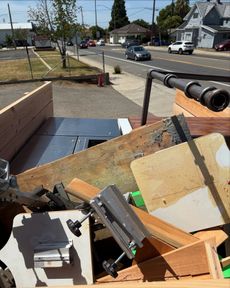 A truck bed filled with wood scraps and a metal pipe pointed towards a street.