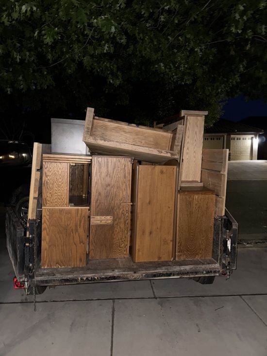 Trailer loaded with wooden furniture, outdoors at night.