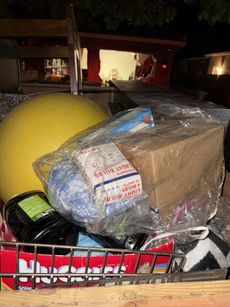 Basket with assorted items, including a yellow ball, wrapped box, and candy boxes.