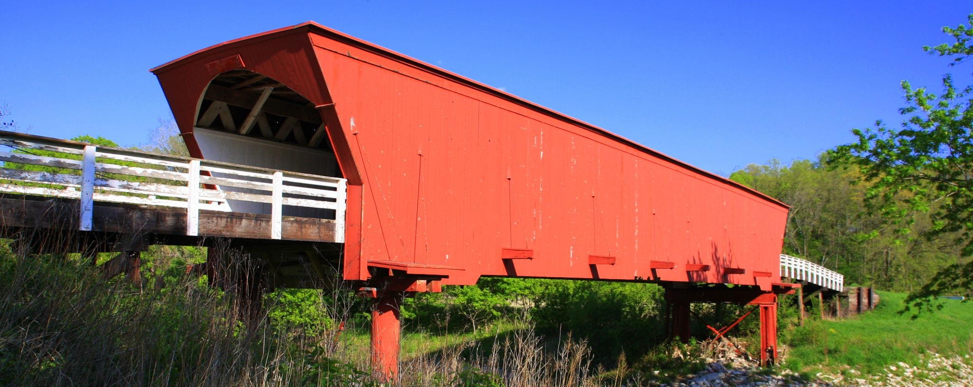 Historic covered bridge in Madison County Iowa surrounded by rural countryside.