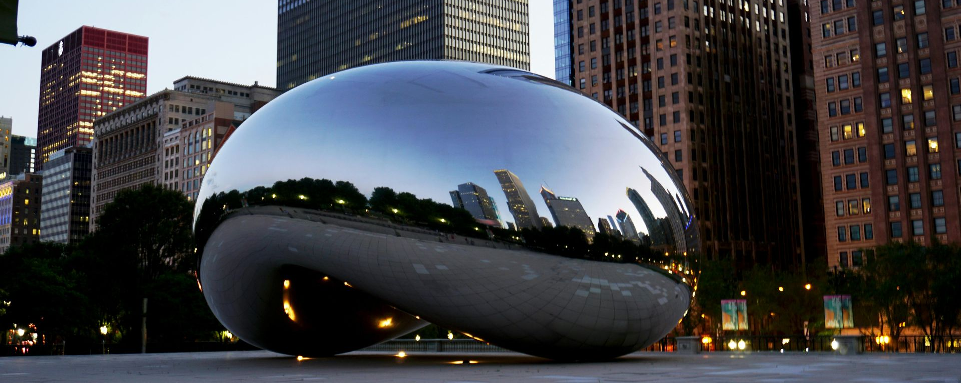 Cloud Gate sculpture known as the Bean reflecting the Chicago skyline and visitors in Millennium Park Chicago Illinois.