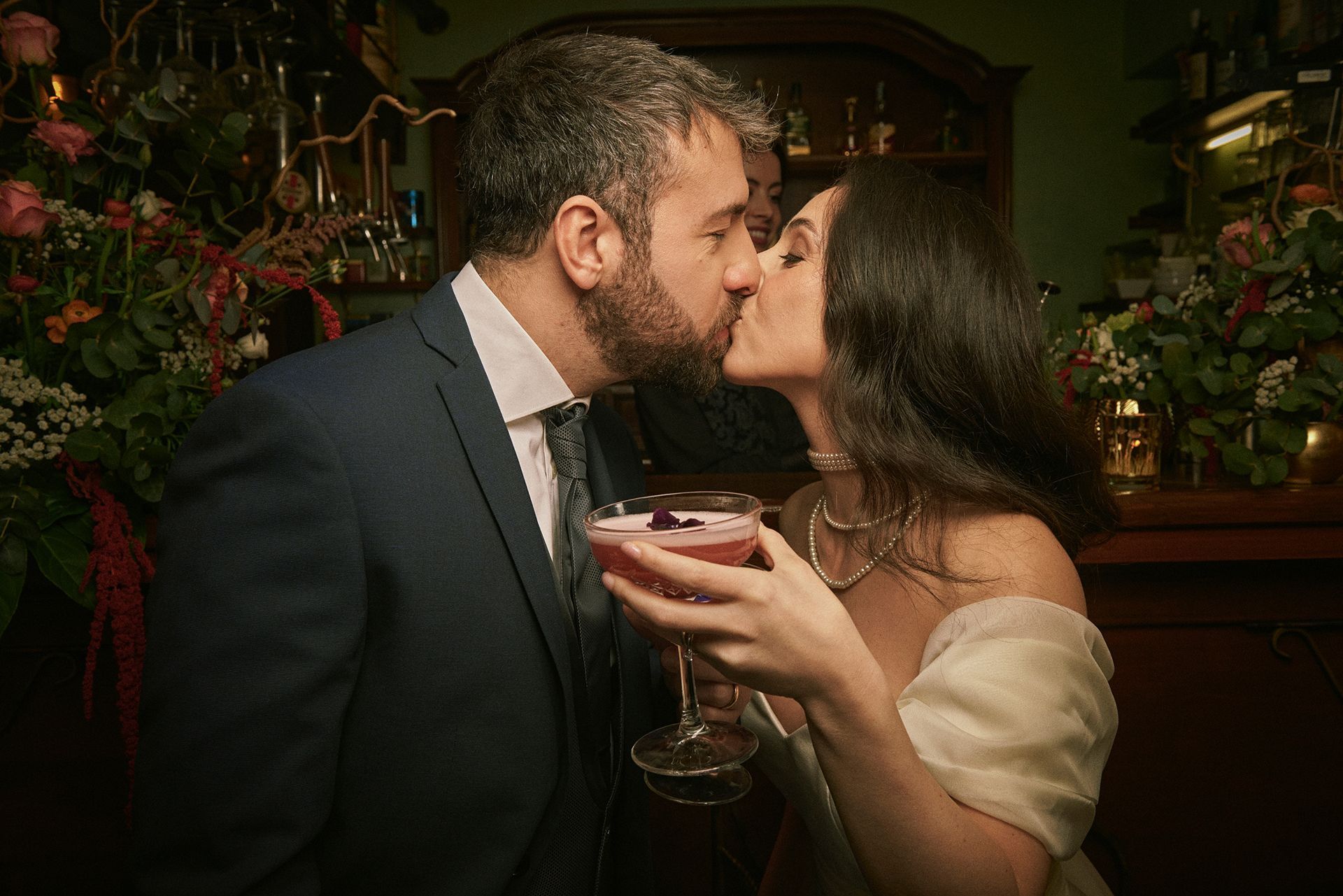 Un uomo e una donna si baciano mentre tengono in mano un drink.