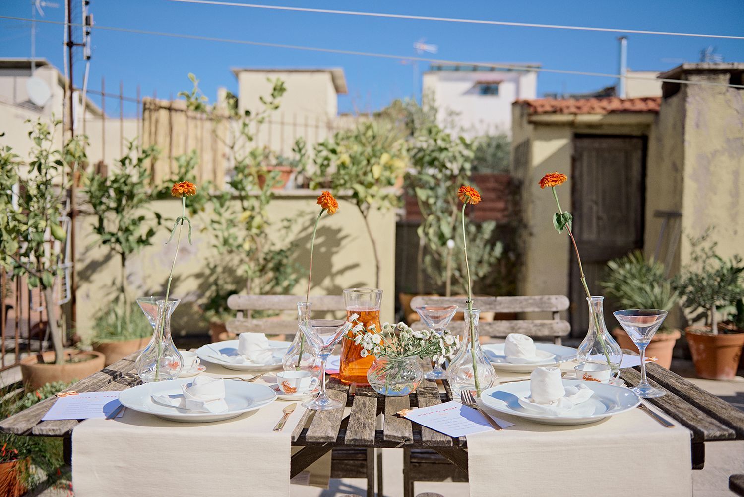 Un tavolo di legno con sopra piatti, bicchieri e vasi.