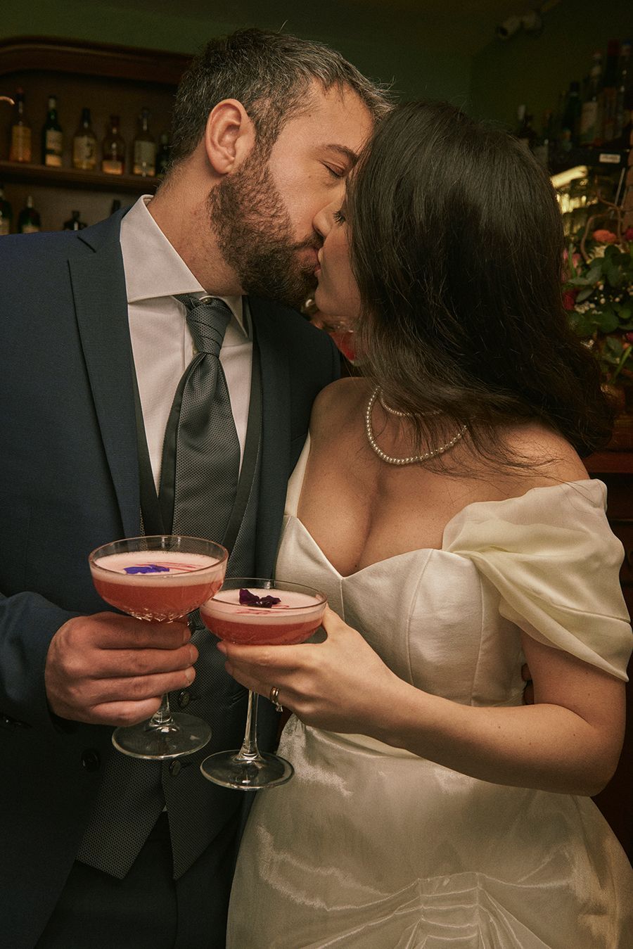 Un uomo e una donna si baciano mentre tengono in mano dei cocktail.