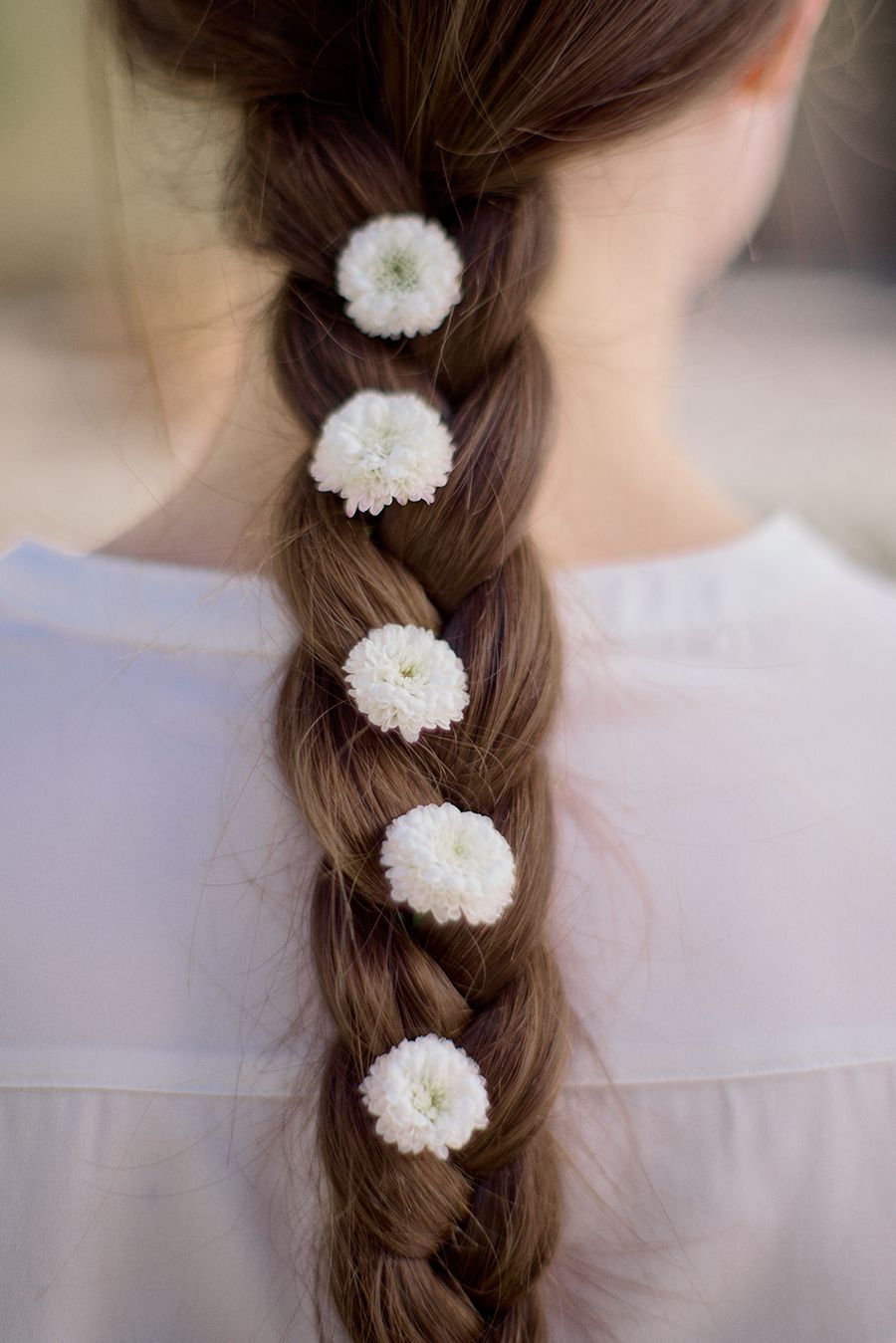 Una donna indossa una treccia con fiori bianchi.