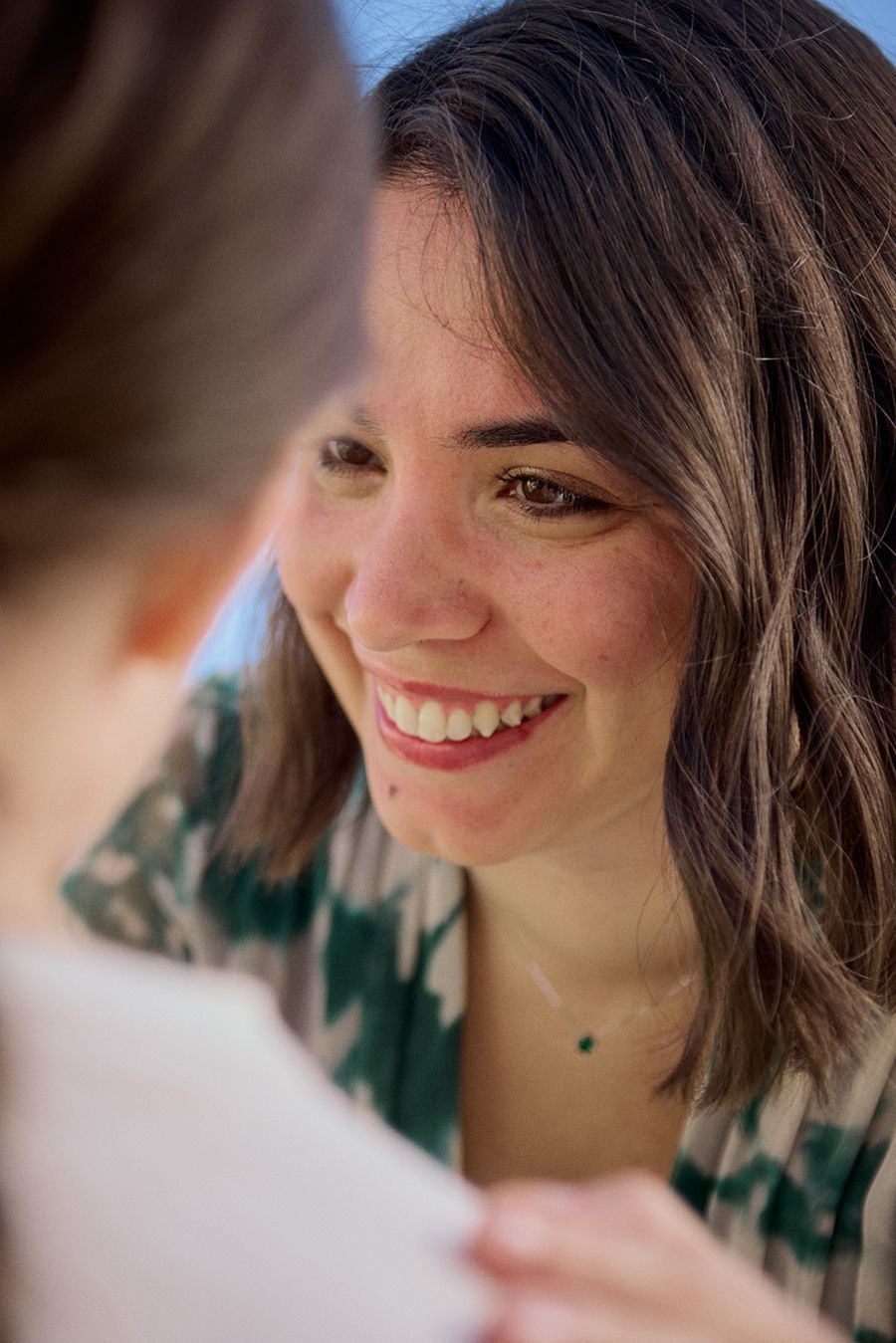 Una donna sorride al suo riflesso in uno specchio.