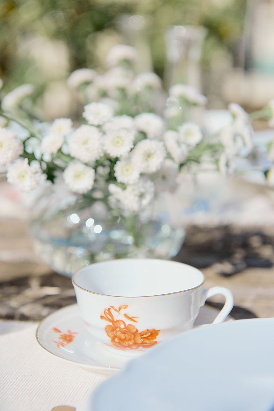 Una tazza e un piattino su un tavolo con un vaso di fiori sullo sfondo.