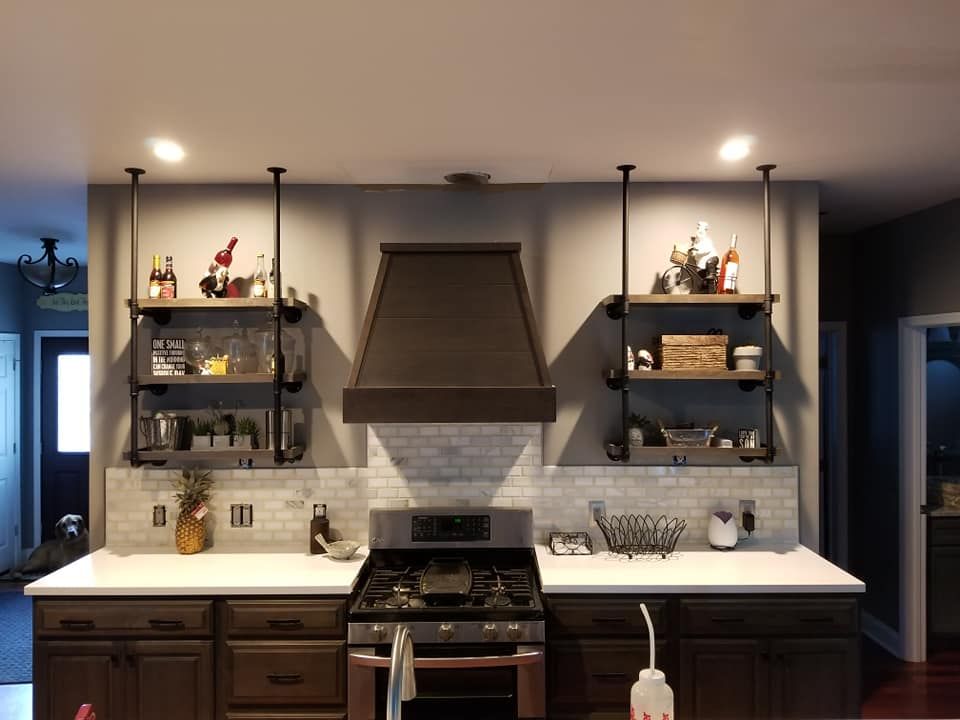 Kitchen with dark cabinets, white countertops, and open shelving made from black pipes.