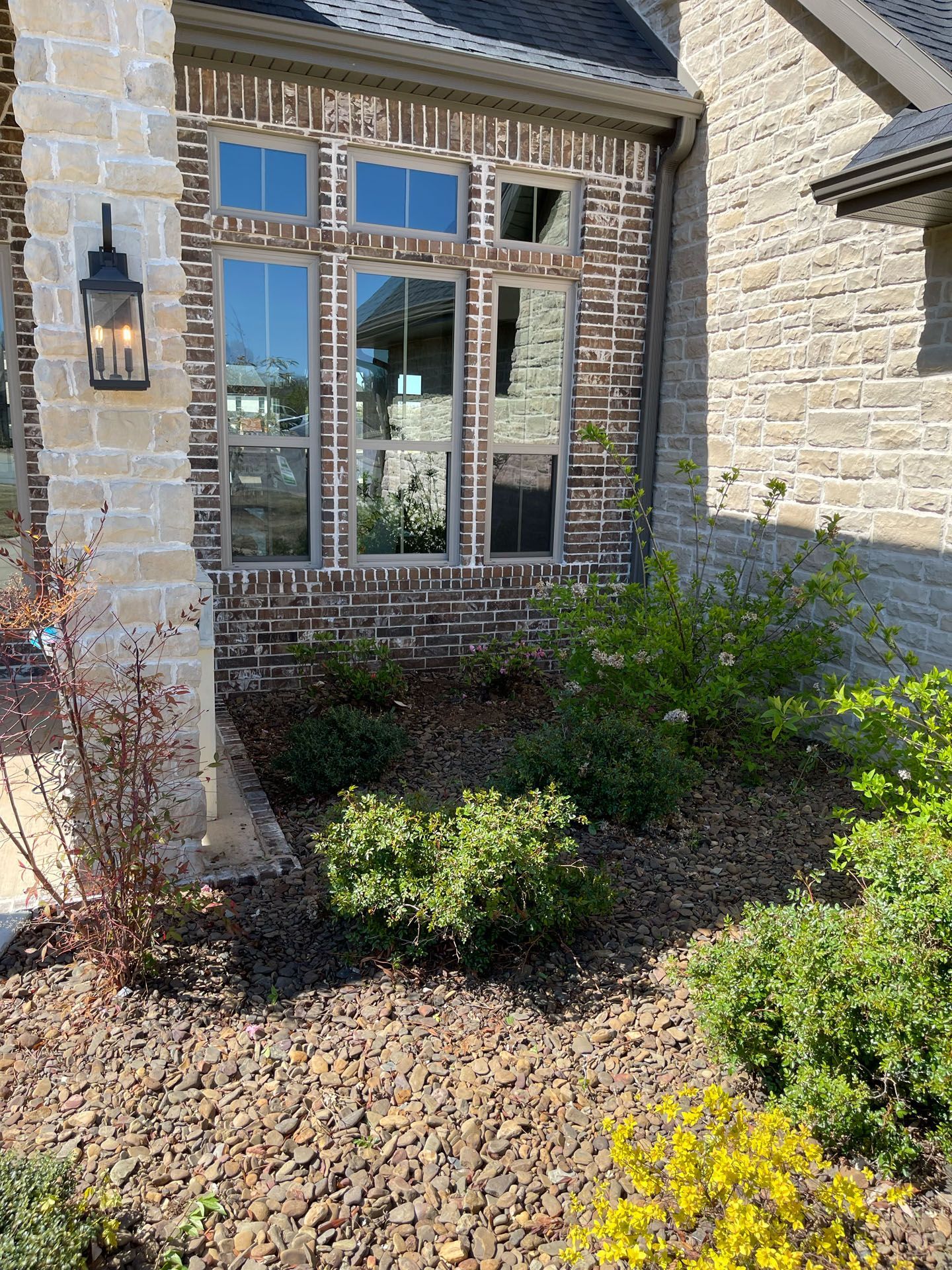 A brick house with a lot of windows and bushes in front of it.