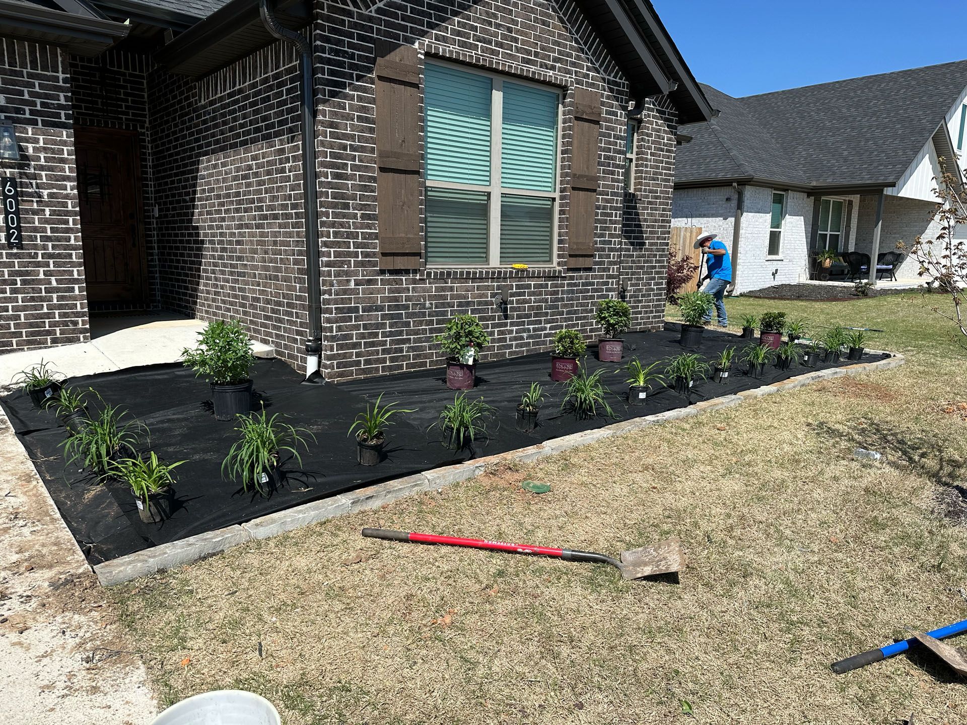 A brick house with a lot of potted plants in front of it.
