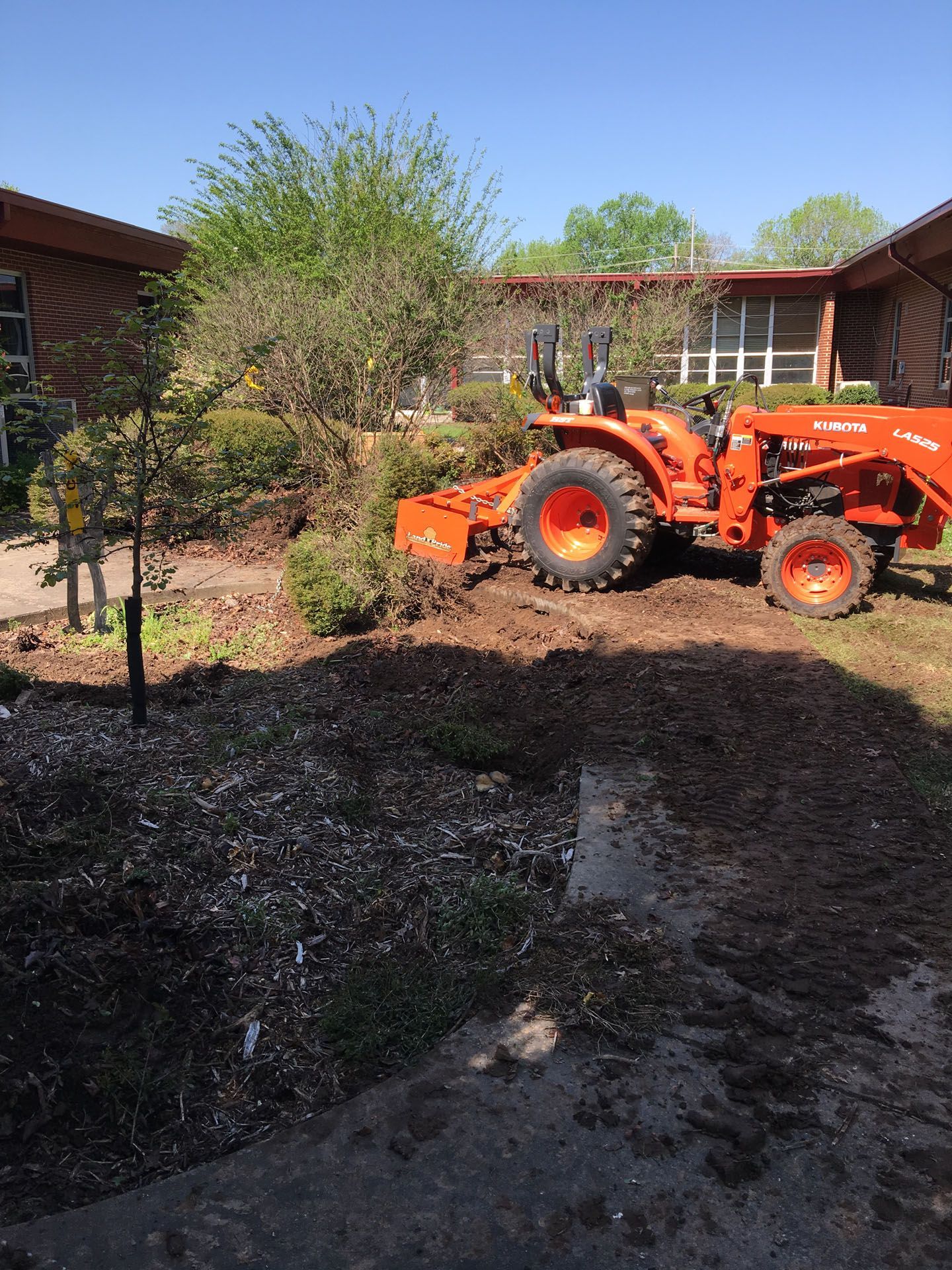 An orange tractor is parked in the dirt in front of a house.