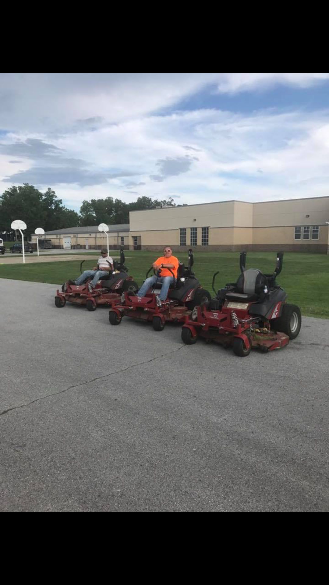 A row of lawn mowers are parked in front of a building.