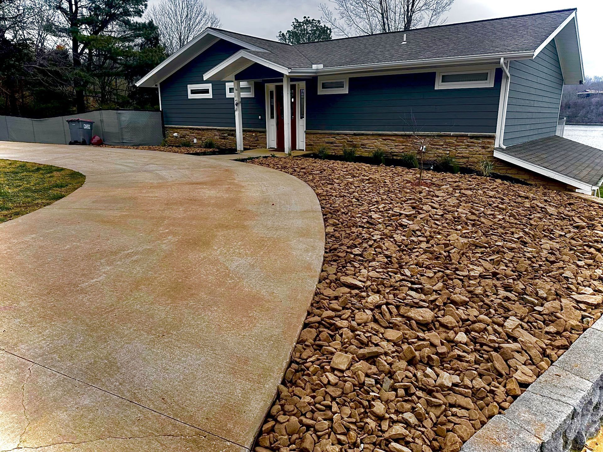 A house with a concrete driveway and gravel in front of it.