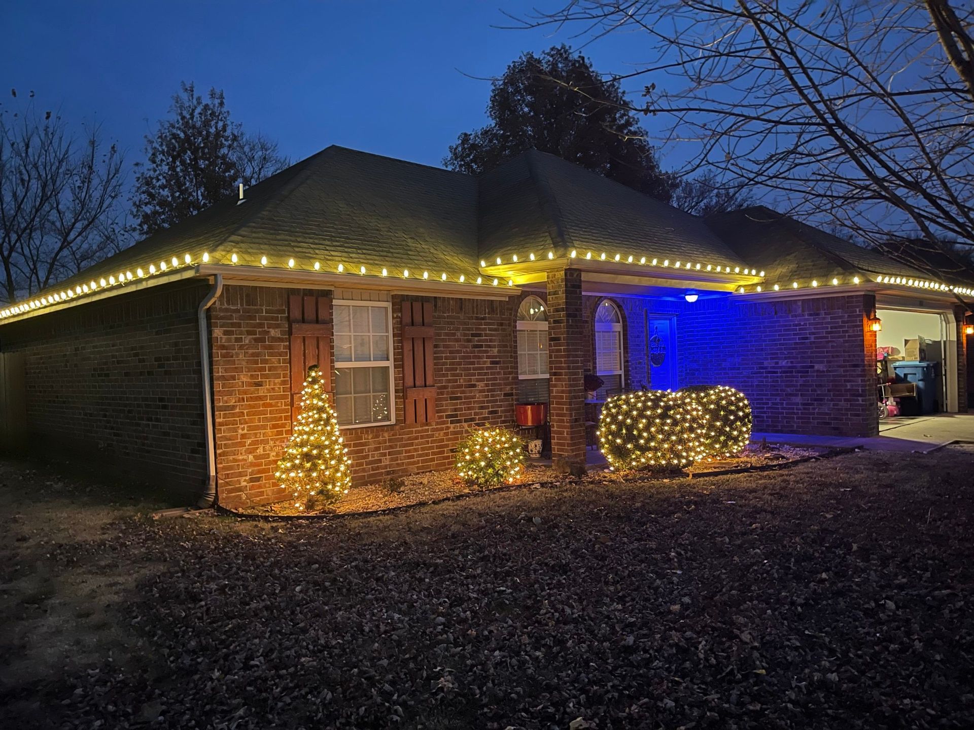 A brick house with christmas lights on it at night.