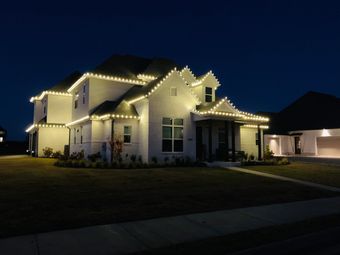 A large white house is lit up with christmas lights at night.