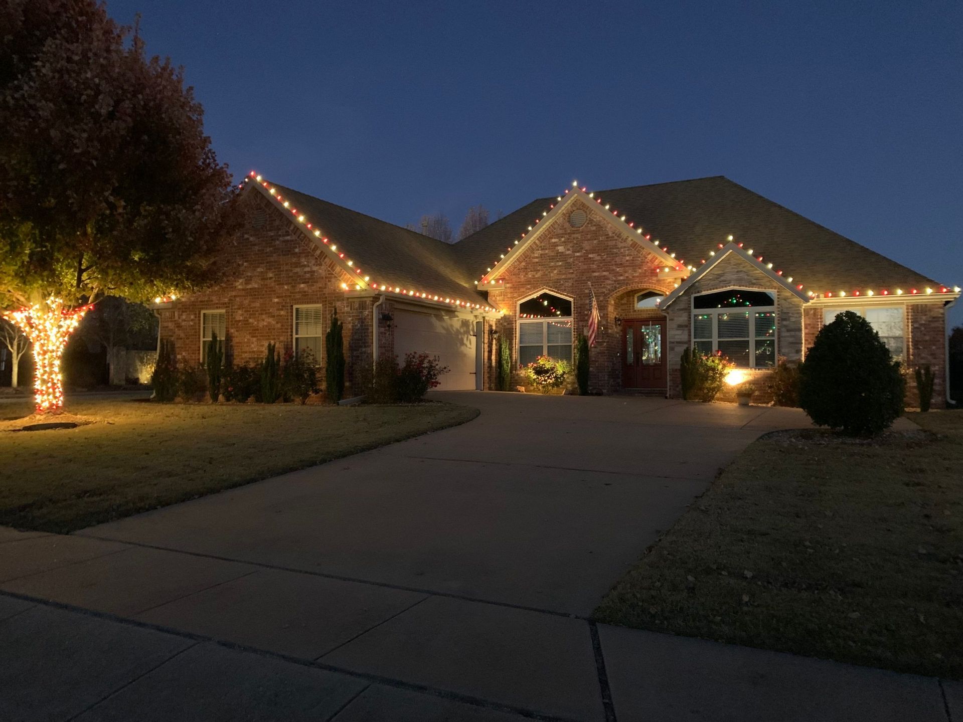 A large house with christmas lights on it is lit up at night.