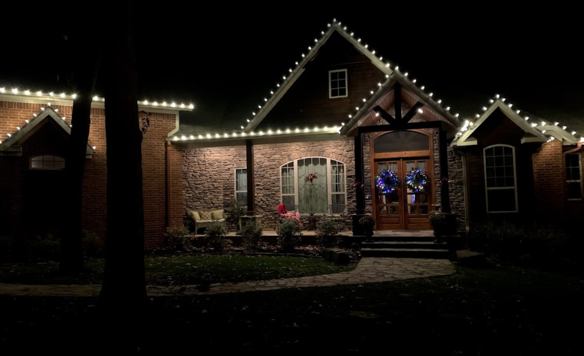 A house with christmas lights on it is lit up at night.