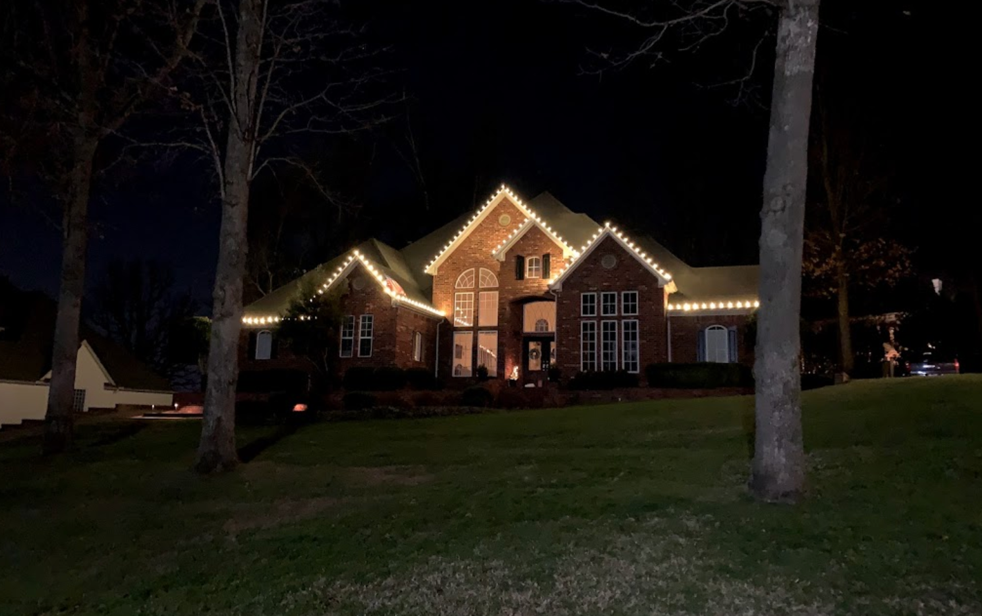 A large house with christmas lights on it is lit up at night.